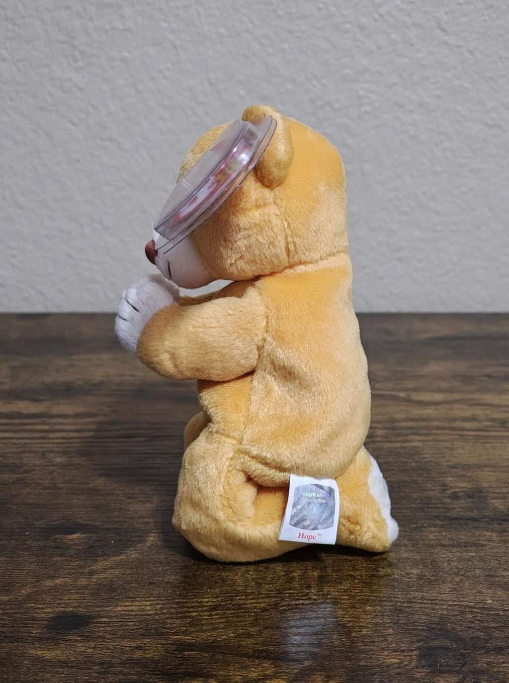 Seated brown plush bear side view with white praying hands and clear Ty heart tag