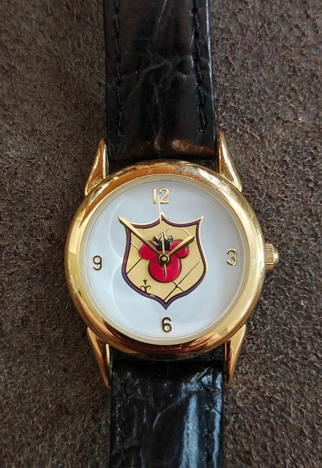 Round gold-tone watch face with Mickey-style logo on black leather strap.