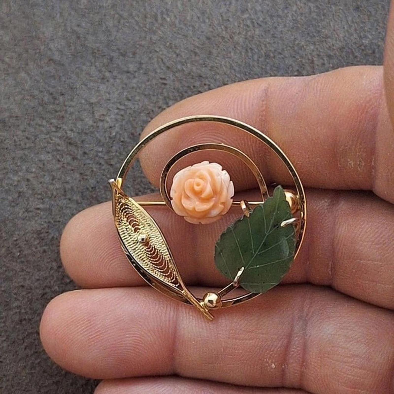 Gold-tone rose-and-leaf filigree brooch with a round frame and pin clasp.