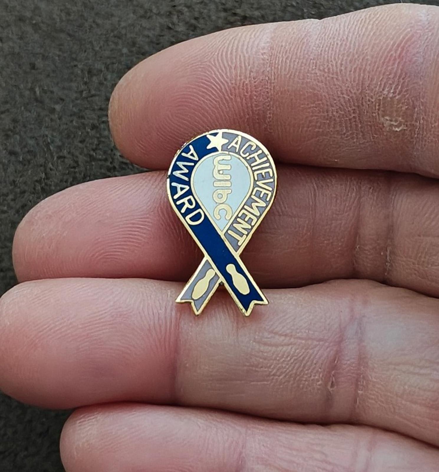 Enamel award pin on blue ribbon design with gold border and circular lettering