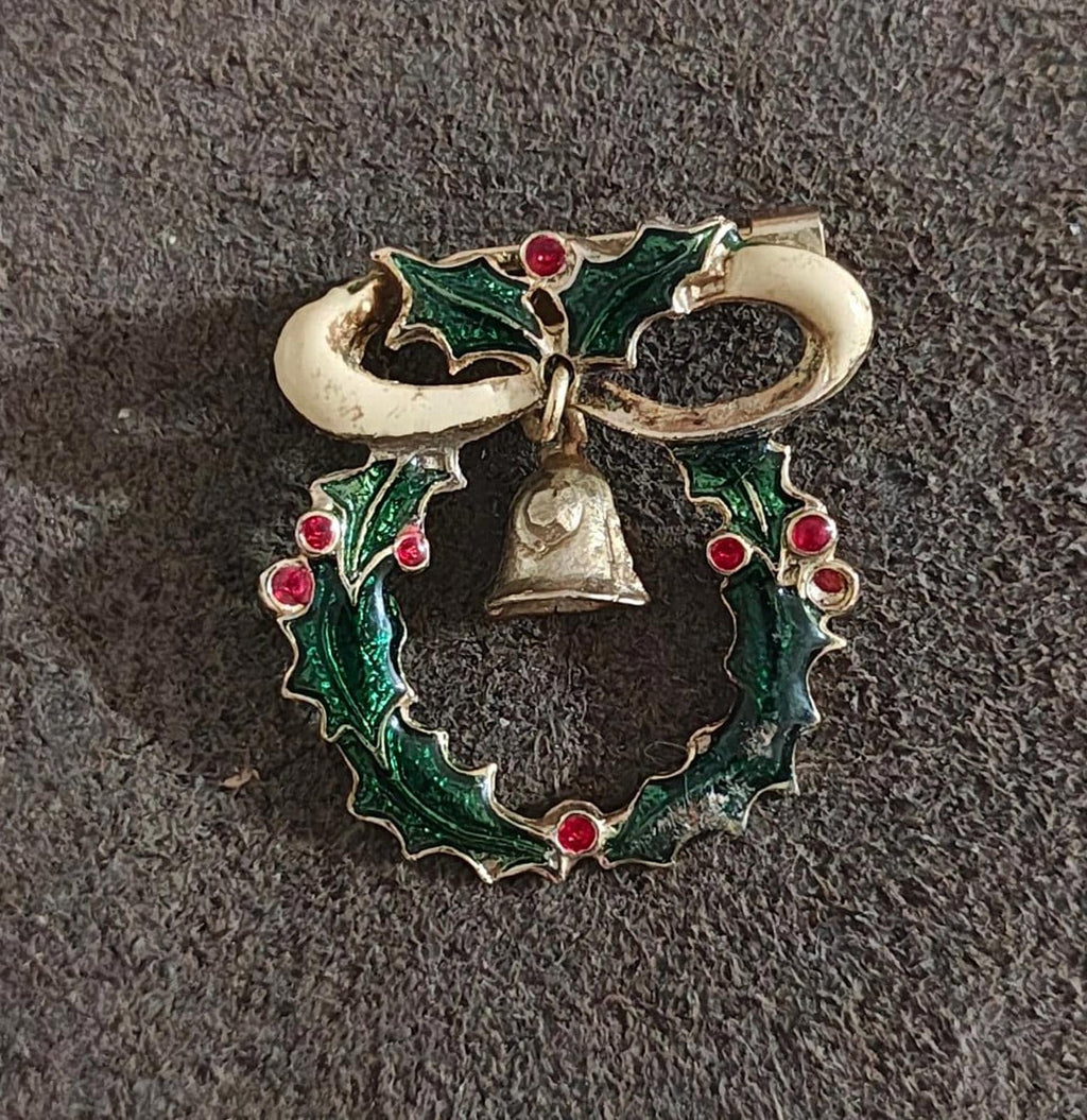 Christmas wreath brooch in green enamel with red berries, gold bell, and ribbon loops