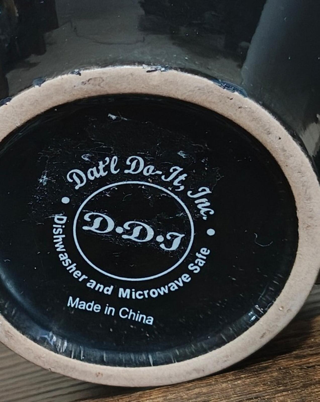 Black mug base close-up with D.D.J logo and dishwasher and microwave-safe text.