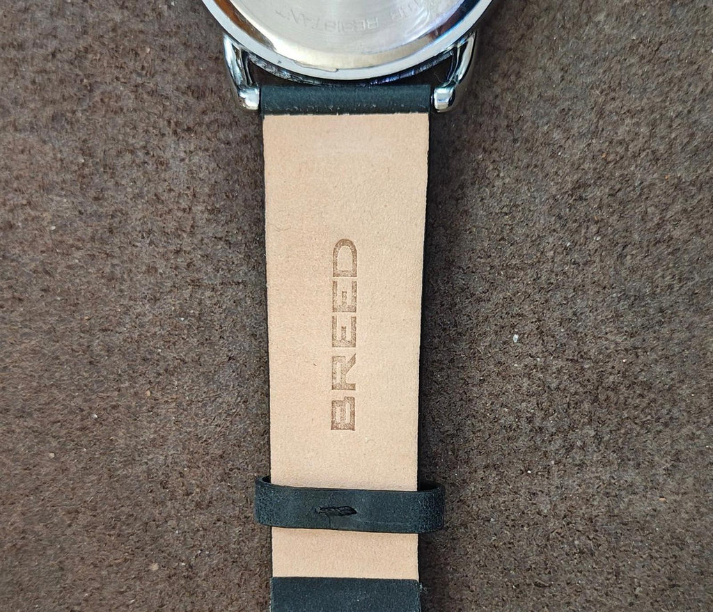 Men's leather-banded watch with light strap, embossed brand text and buckle