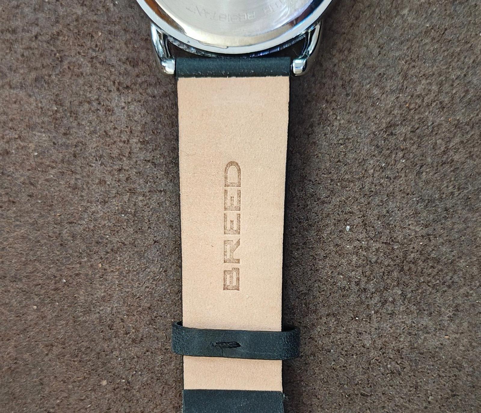 Men's leather-banded watch with light strap, embossed brand text and buckle