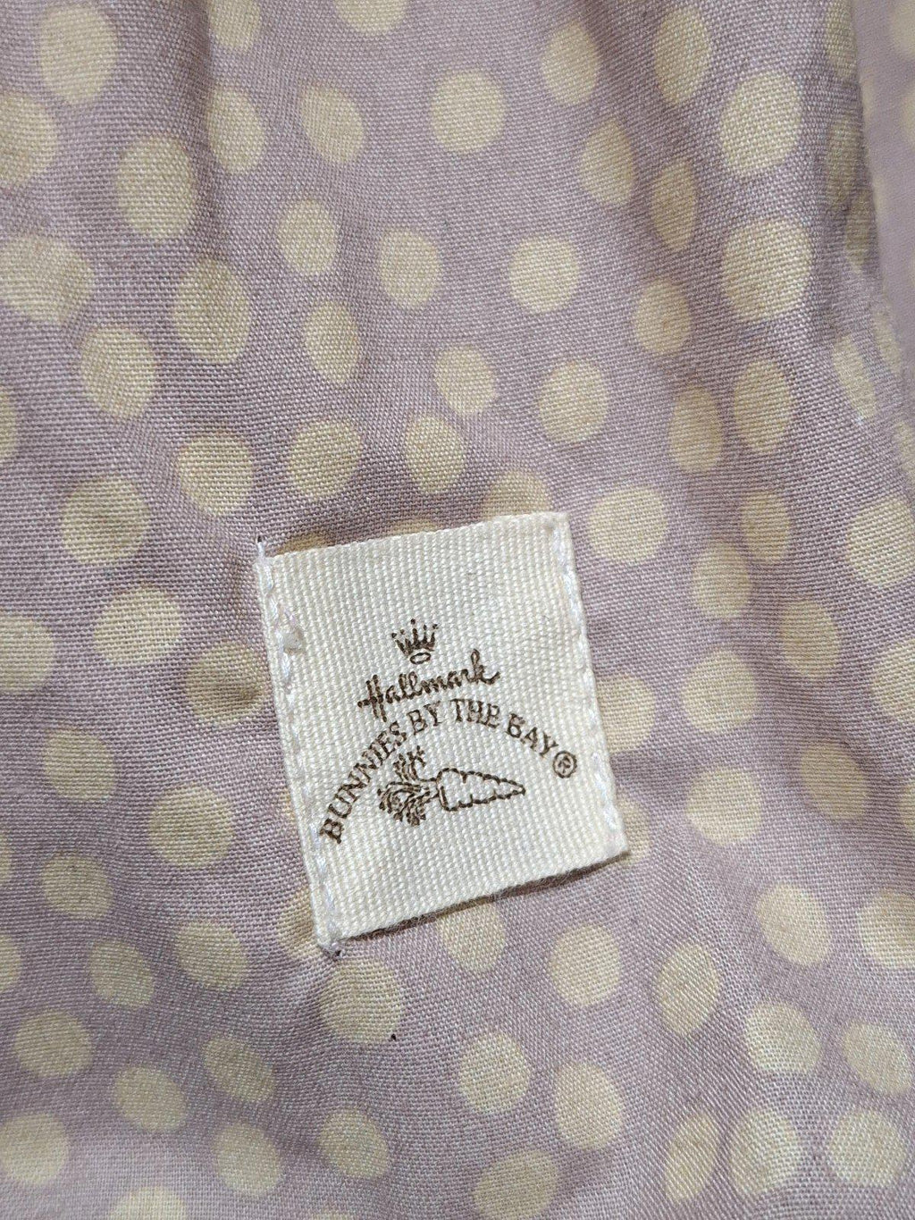 Fabric label on plush dress, reading "BUNNIES BY THE BAY" with carrot graphic