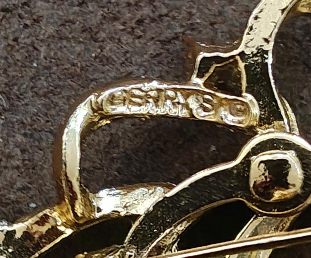 Close-up of gold-tone brooch clasp and rhinestone-set details