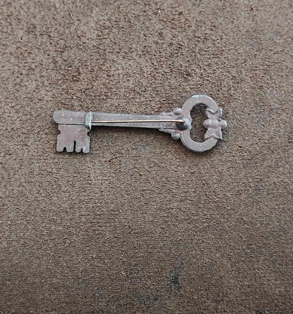 Pewter skeleton key brooch lying flat, key bow and notched teeth visible