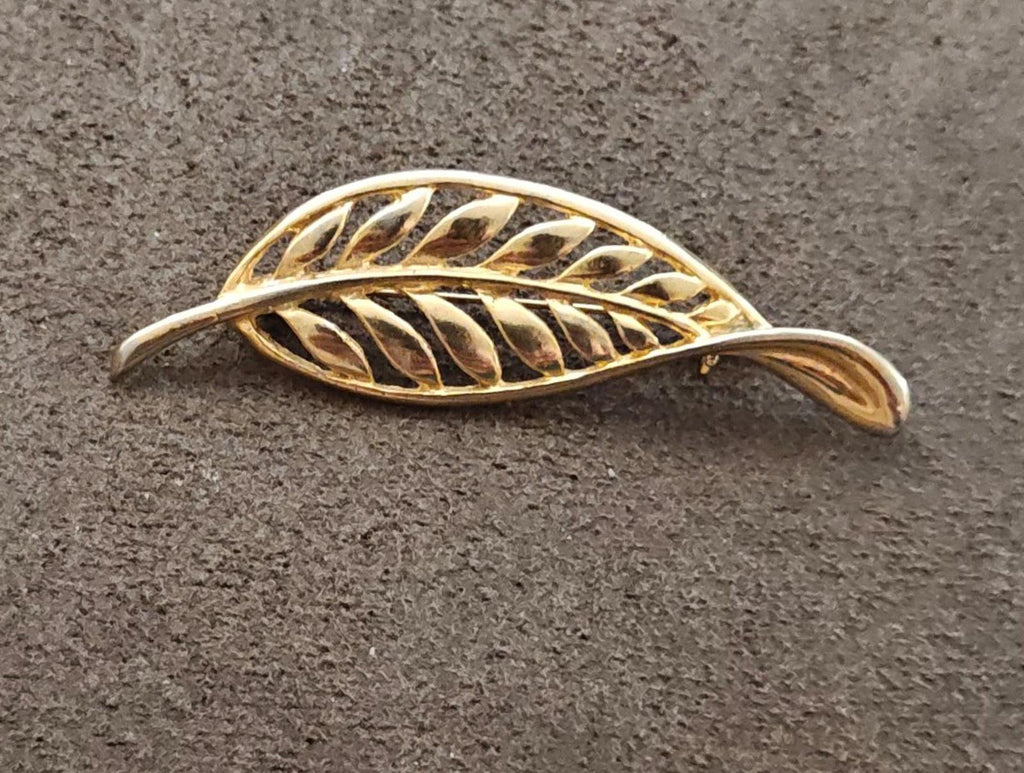 Gold tone leaf brooch with openwork filigree feather motif, angled top view