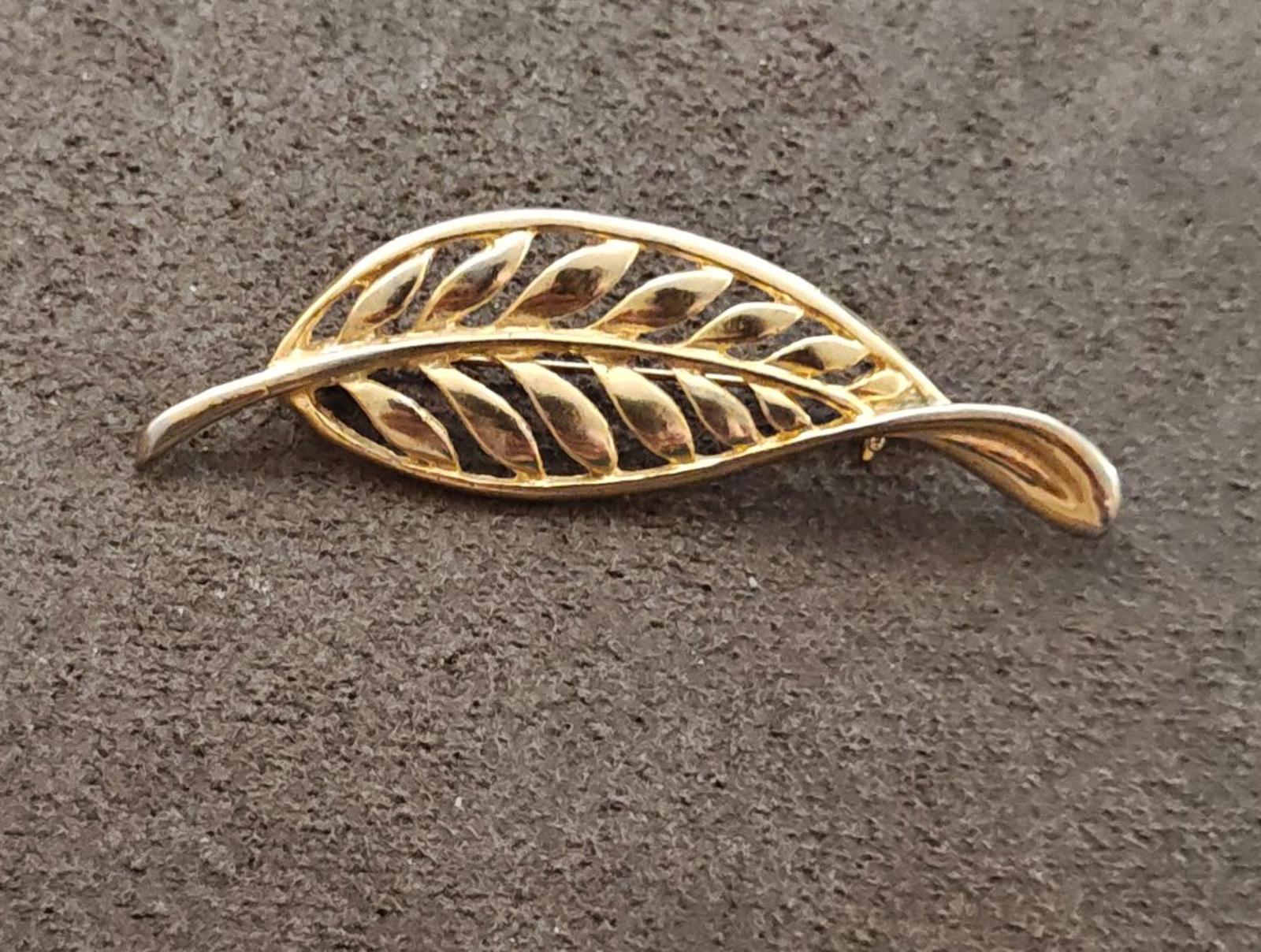 Gold tone leaf brooch with openwork filigree feather motif, angled top view