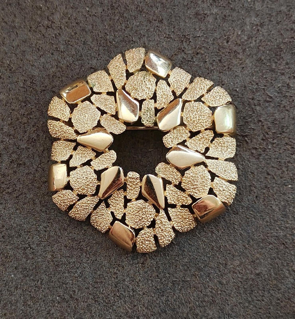 Gold-tone textured wreath brooch with raised irregular stones around the rim