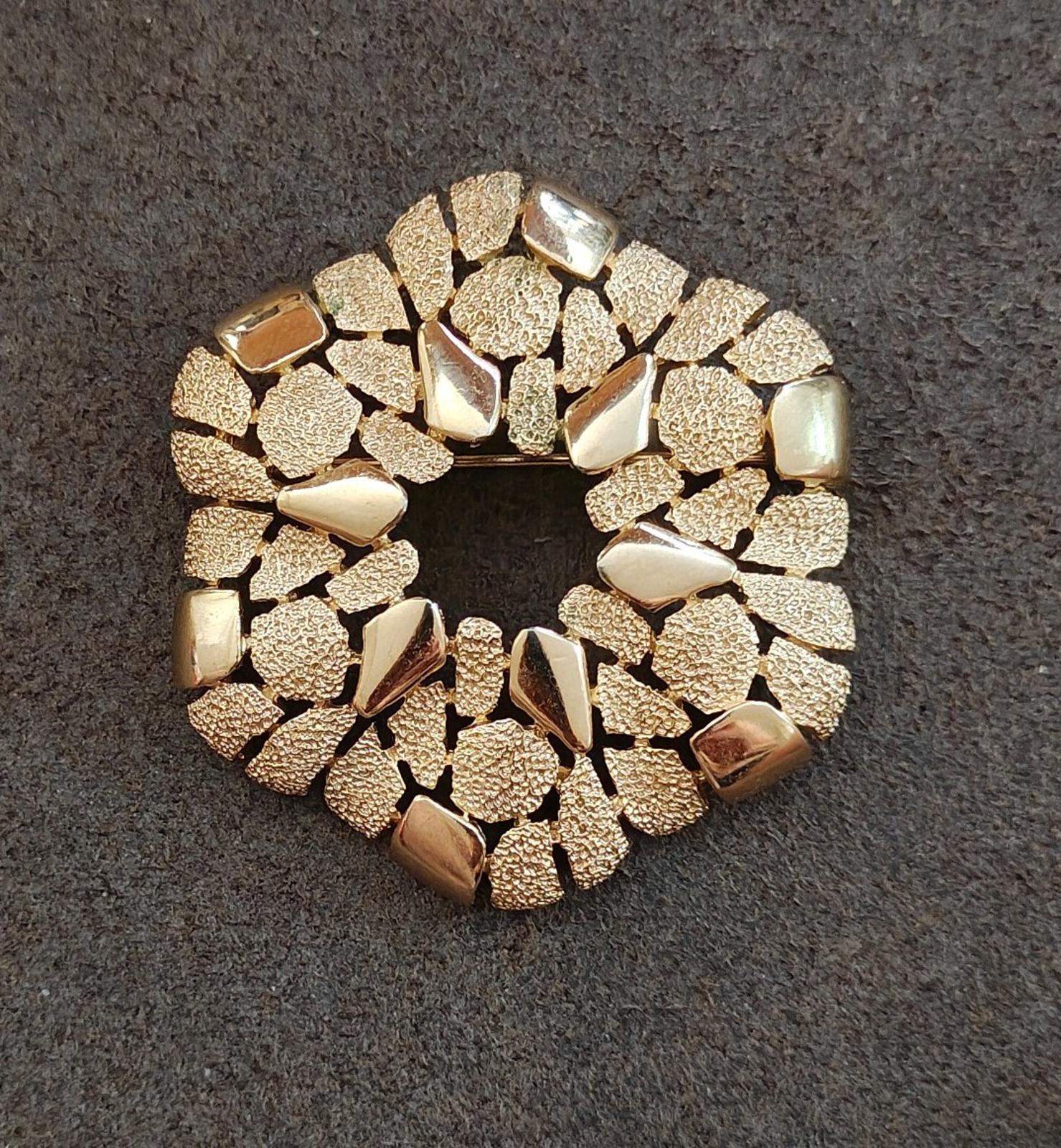 Gold-tone textured wreath brooch with raised irregular stones around the rim
