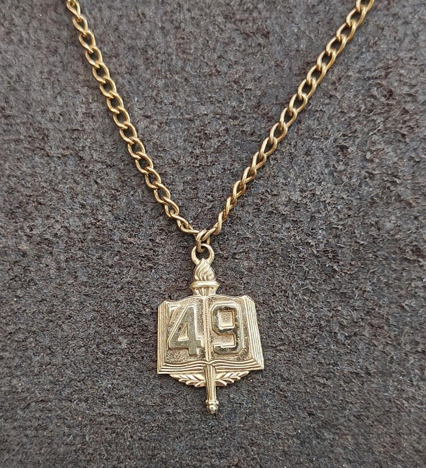 Gold-tone book charm marked 49 on a linked chain