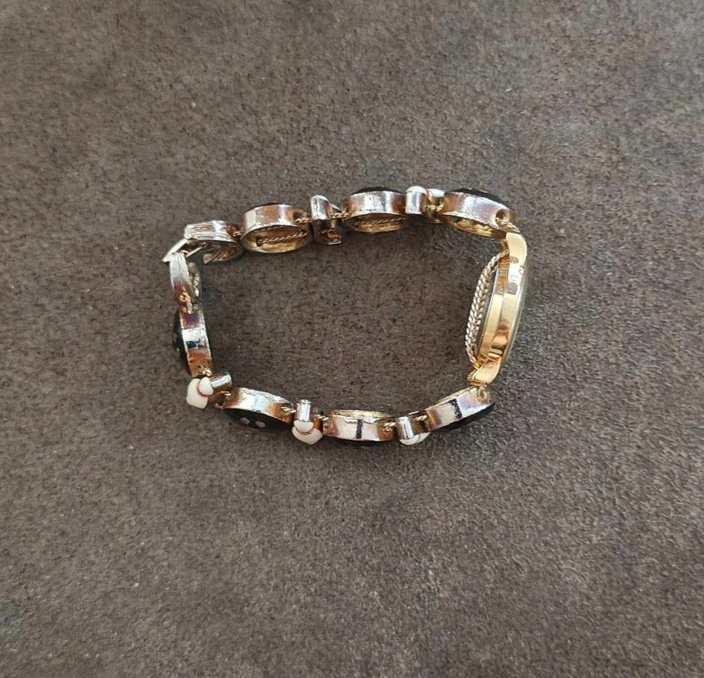 Bracelet band with alternating gold-tone oval links and black segments; circular clasp