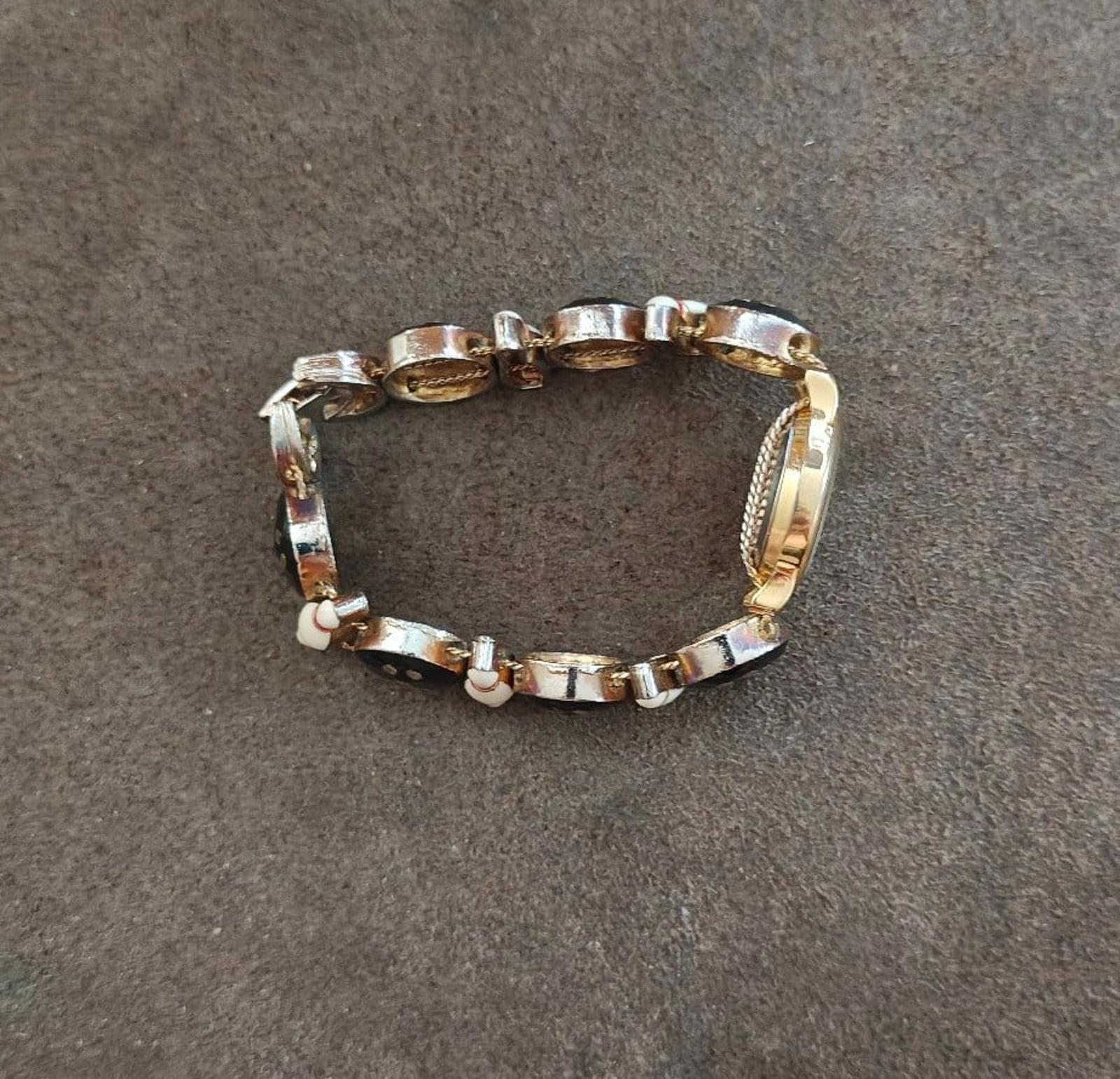 Bracelet band with alternating gold-tone oval links and black segments; circular clasp
