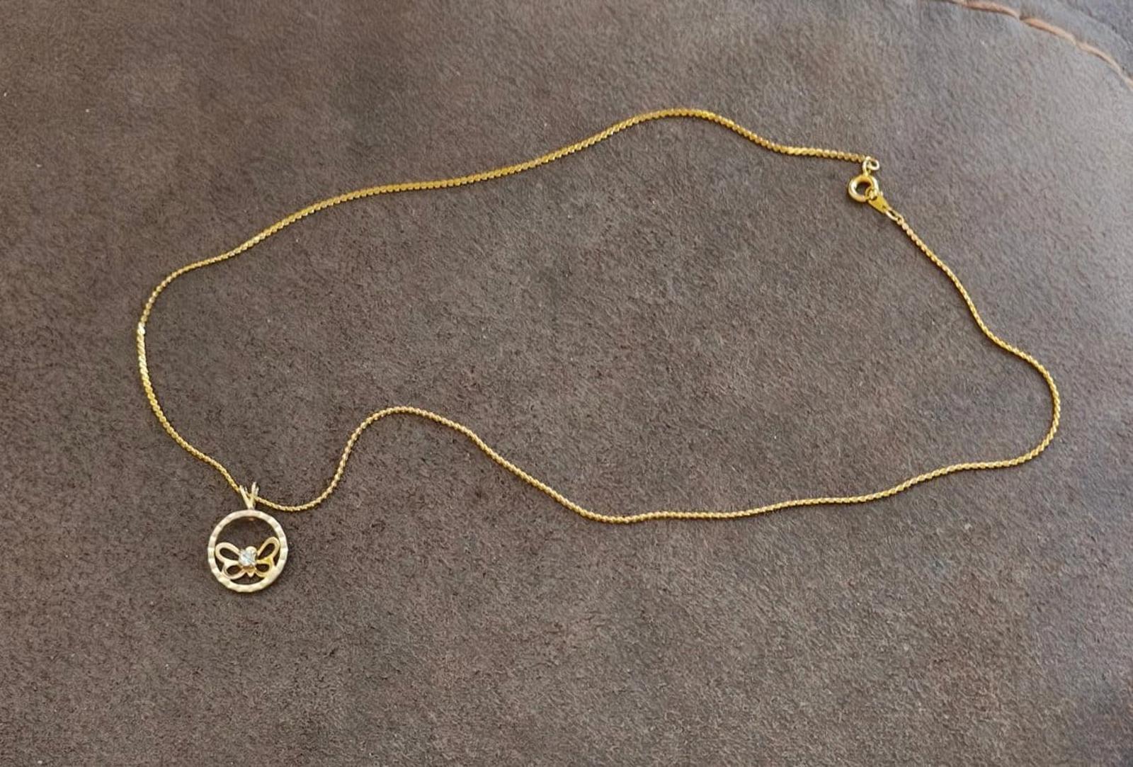 Gold-tone chain necklace with round butterfly pendant and small matching charm at end