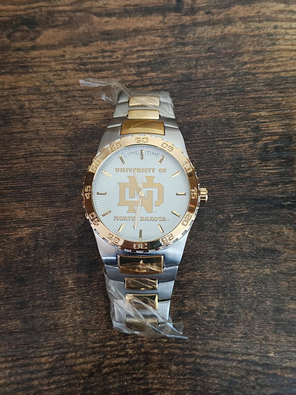 Gold and silver sports watch with white dial and University of North Dakota logo