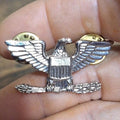 Silver-tone eagle rank pin with spread wings and central shield detail, gold accents