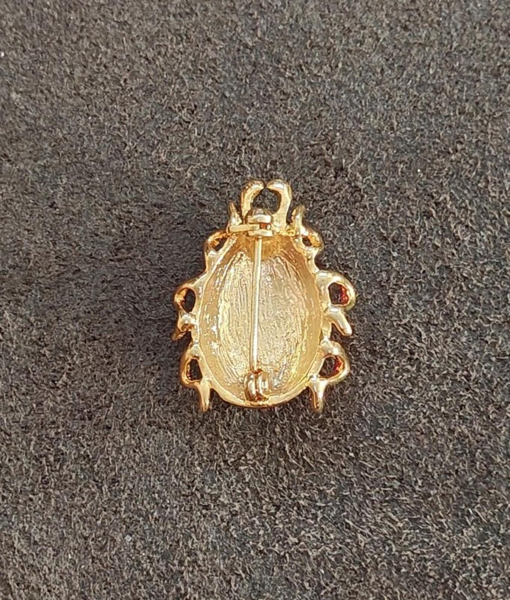 Back of gold-tone ladybug brooch with smooth enamel backplate and small side loops