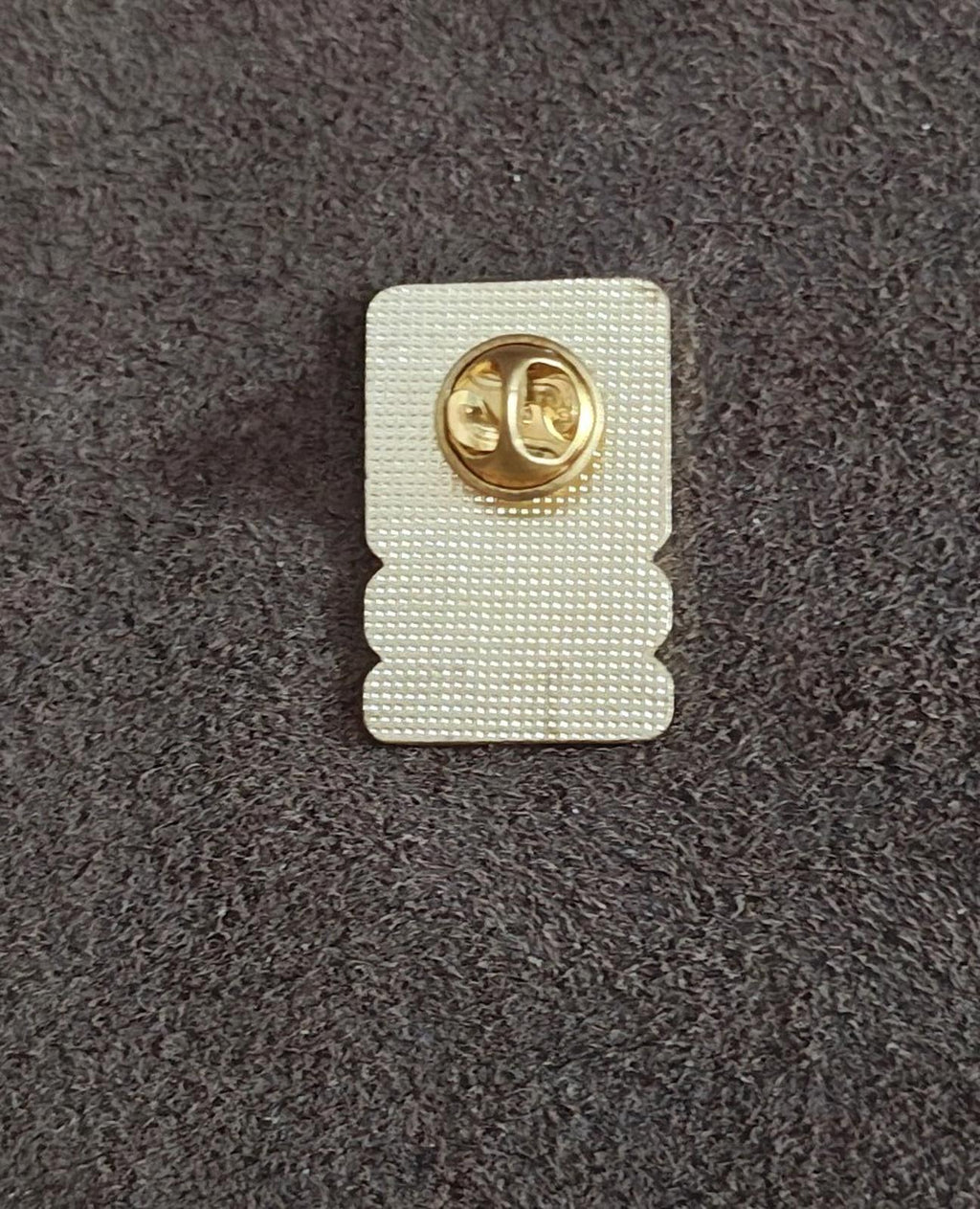 Back of U.S. Army star lapel pin with white backing and gold metal clasp