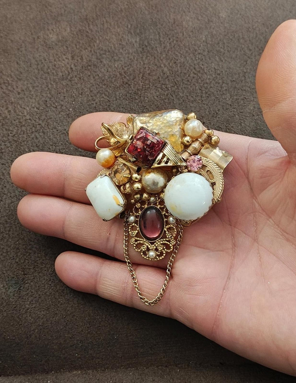 Gold-tone vintage brooch with faux pearls, white stones, pink accents, red square gem, and chain