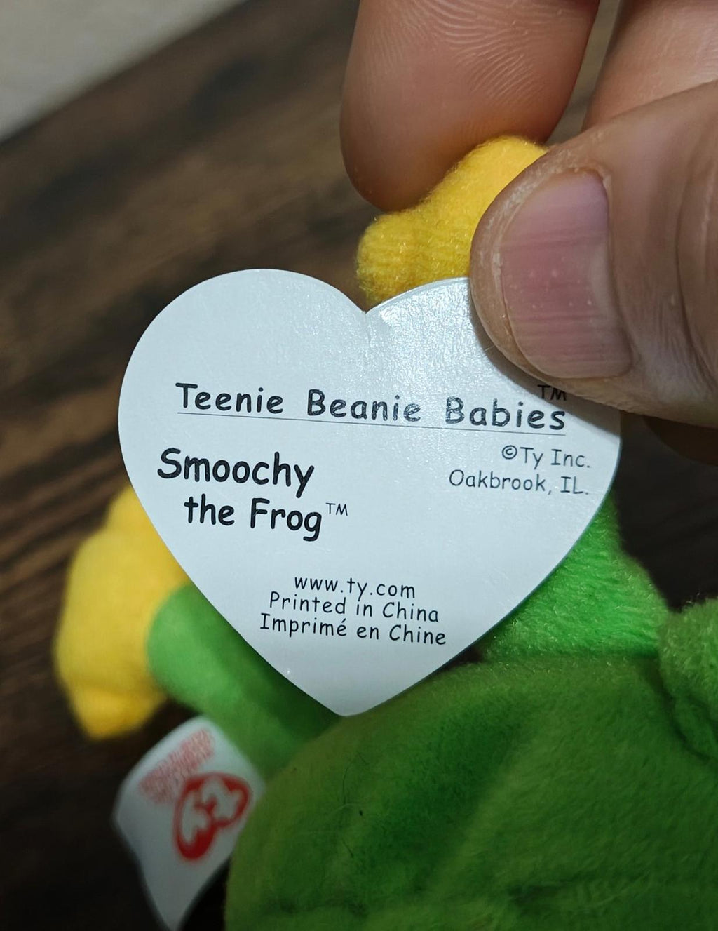 Heart-shaped Ty swing tag reading 'Smoochy the Frog' on green plush