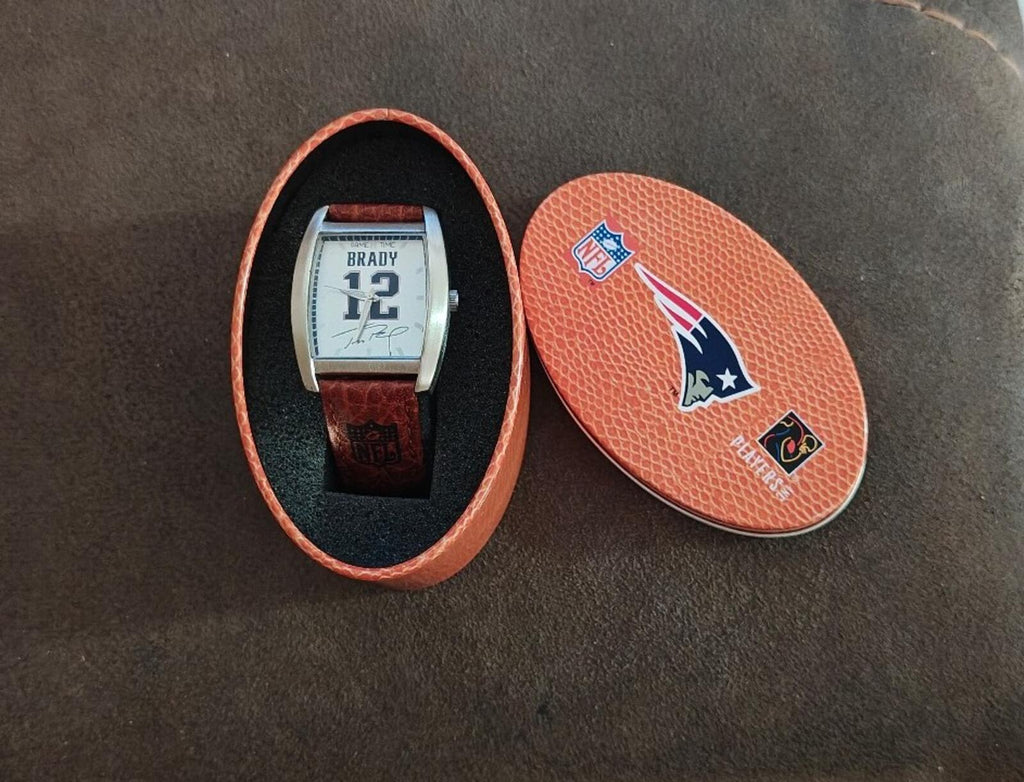 Tom Brady watch resting in a separate orange logo case lid with team emblem.