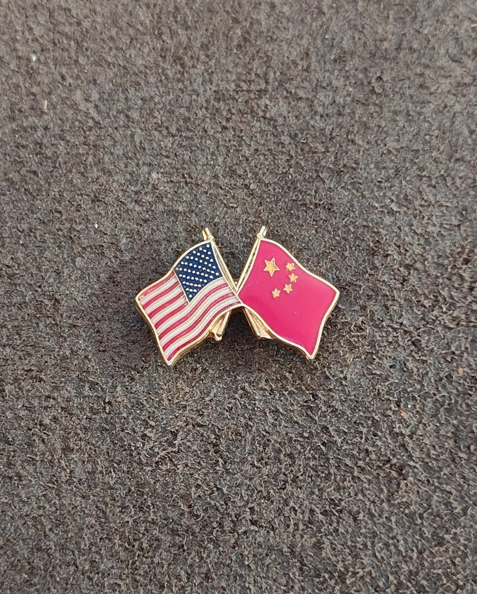 Enamel friendship lapel pin showing crossed US flag and pink China flag with gold edges.