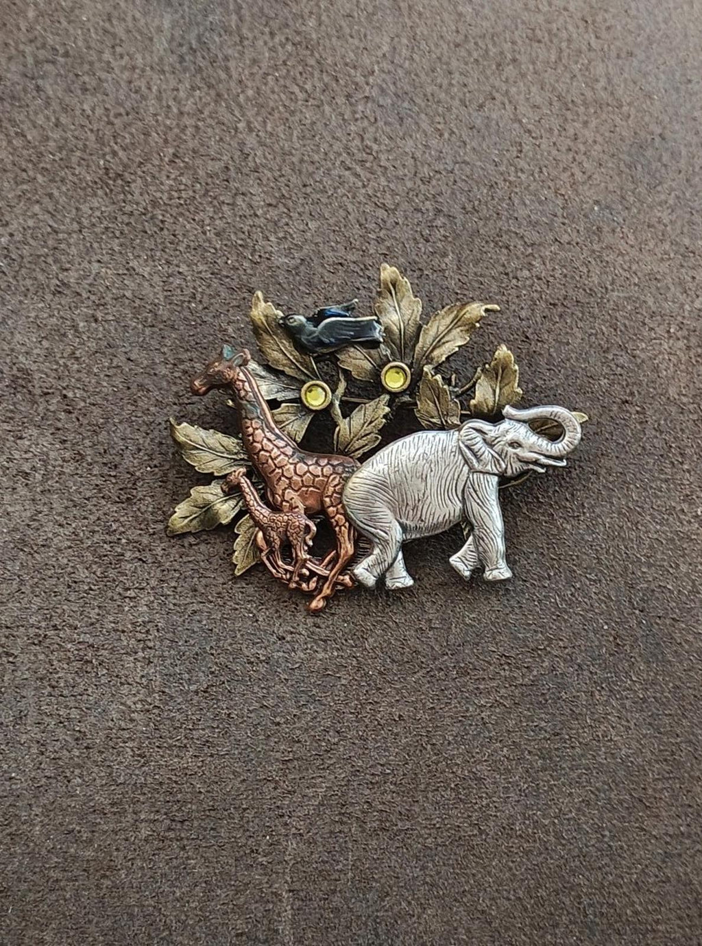 Safari-themed brooch featuring a silver-tone elephant and foliage over a mixed-metal design