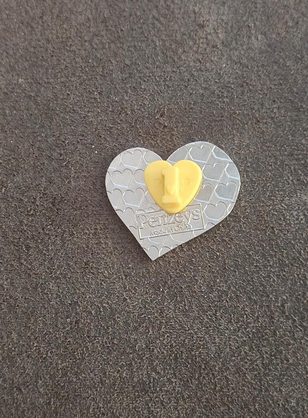 Back of heart pin, silver tone with textured hearts and a yellow pin post.