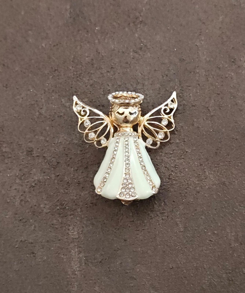 Gold tone angel brooch with crystal-like dots, cream dress, and openwork wings