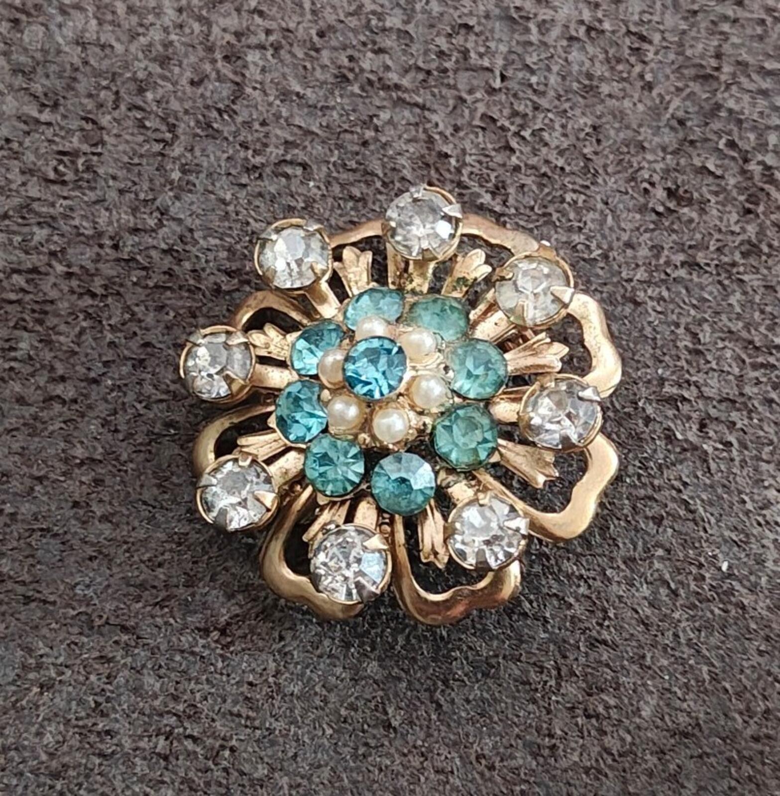Gold-tone floral sunburst pin with teal gemstone-like stones, faux pearl center, rhinestones