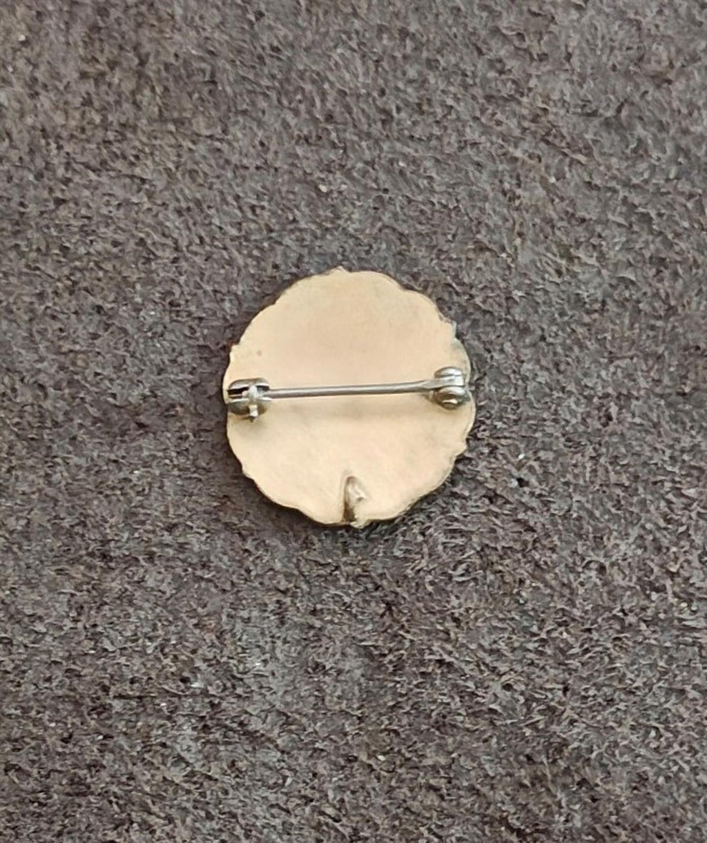 Back of round enamel pin with gold finish and straight pin clasp