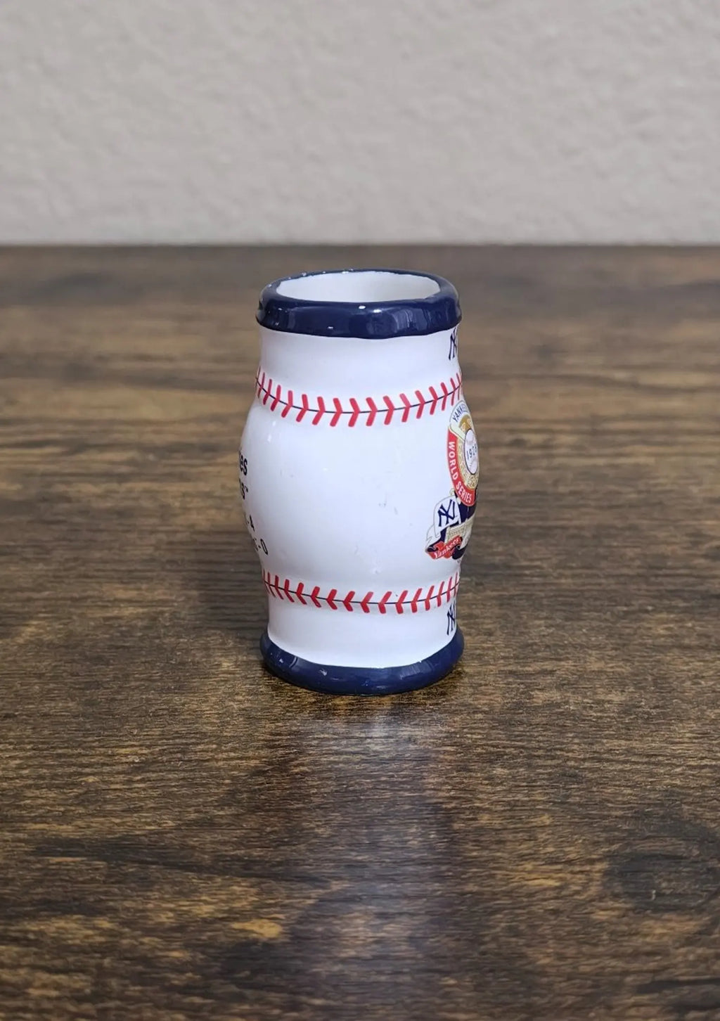 Miniature ceramic mug side view, white with navy top and base; red stitch trim