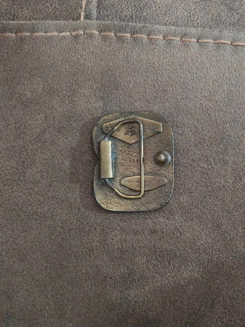 Vintage brass belt buckle back view with metal loop and round mounting rivet.