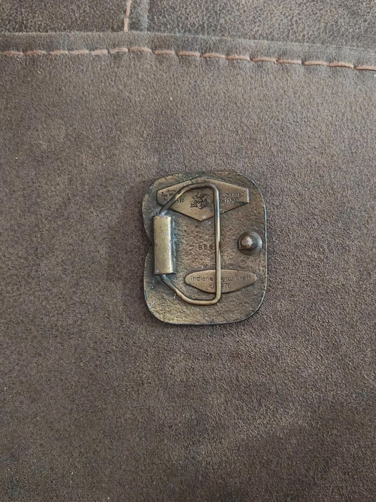 Vintage brass belt buckle back view with metal loop and round mounting rivet.