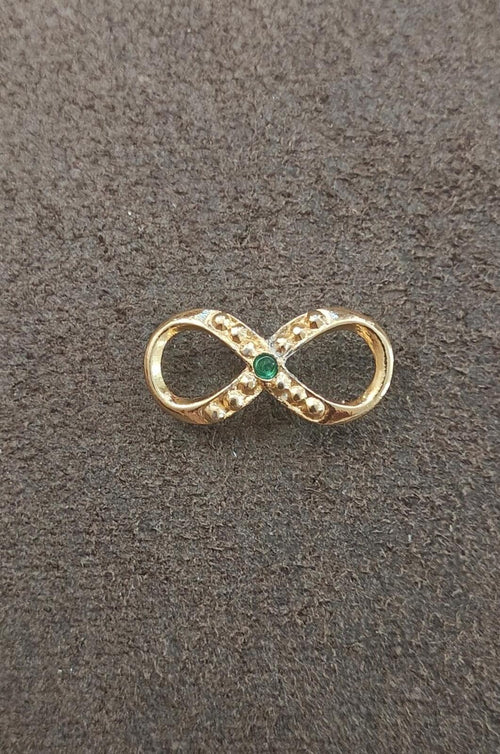 Gold infinity brooch with green emerald center and clear stone detailing