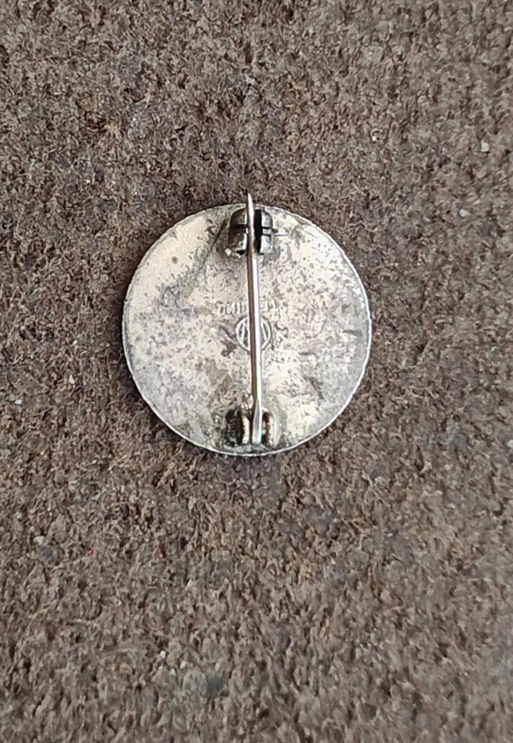 Back of a round silver-tone enamel service pin with hinged clasp and pin post