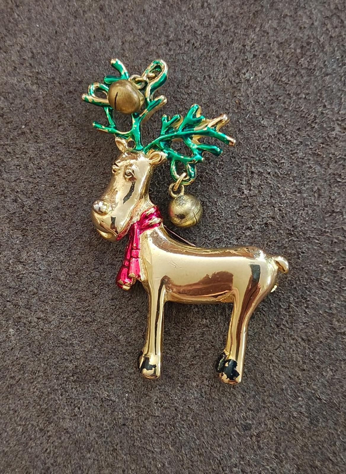 Gold-tone reindeer pin brooch with green antlers, red scarf, and bell ornaments.