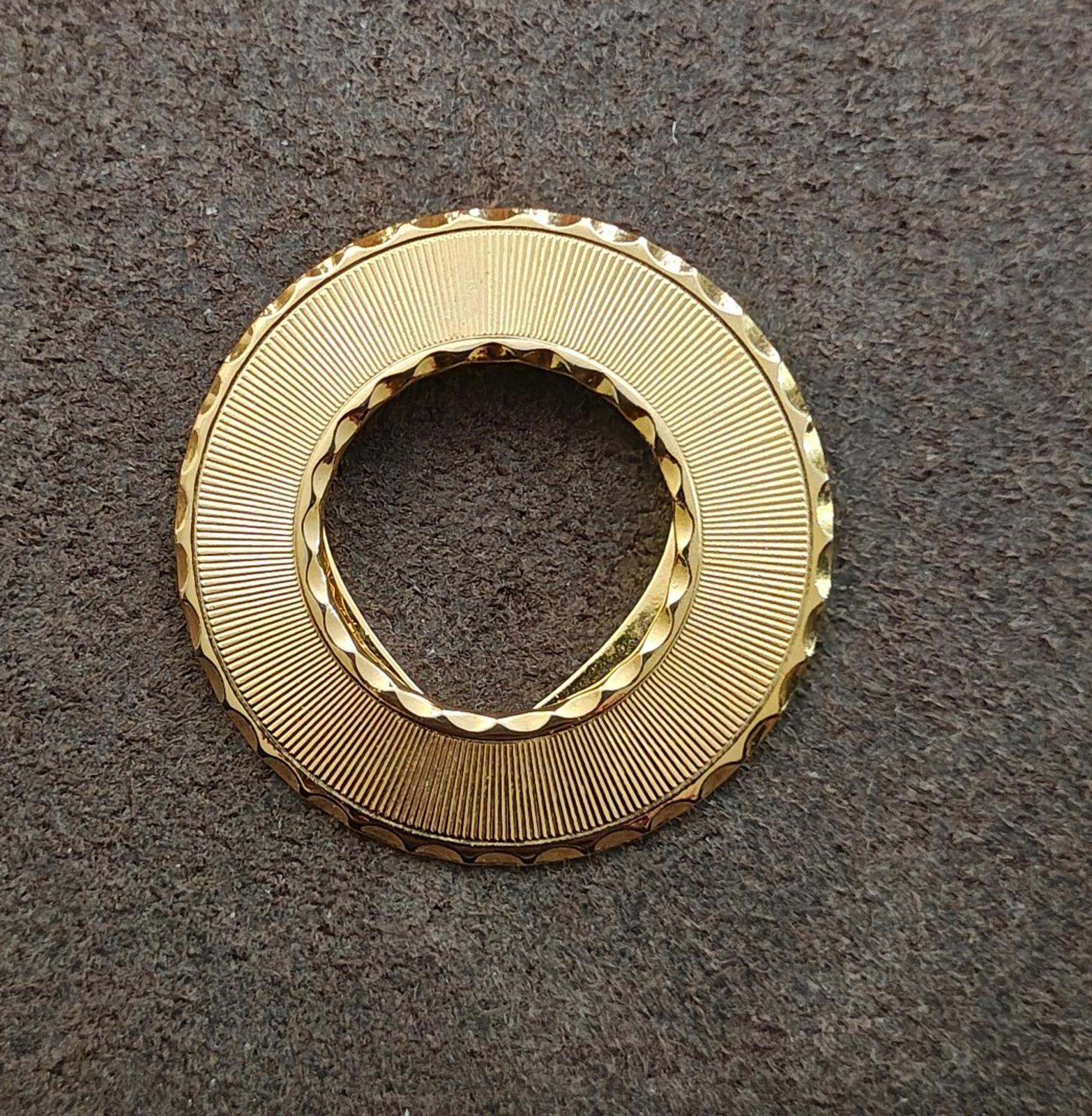 Gold-tone round scarf clip with ribbed outer ring and inner ring, clasp open
