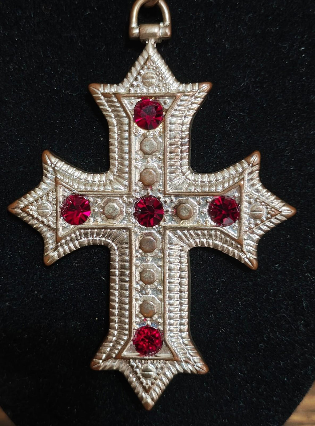Silver tone cross pendant necklace with red rhinestone starburst details and bail loop