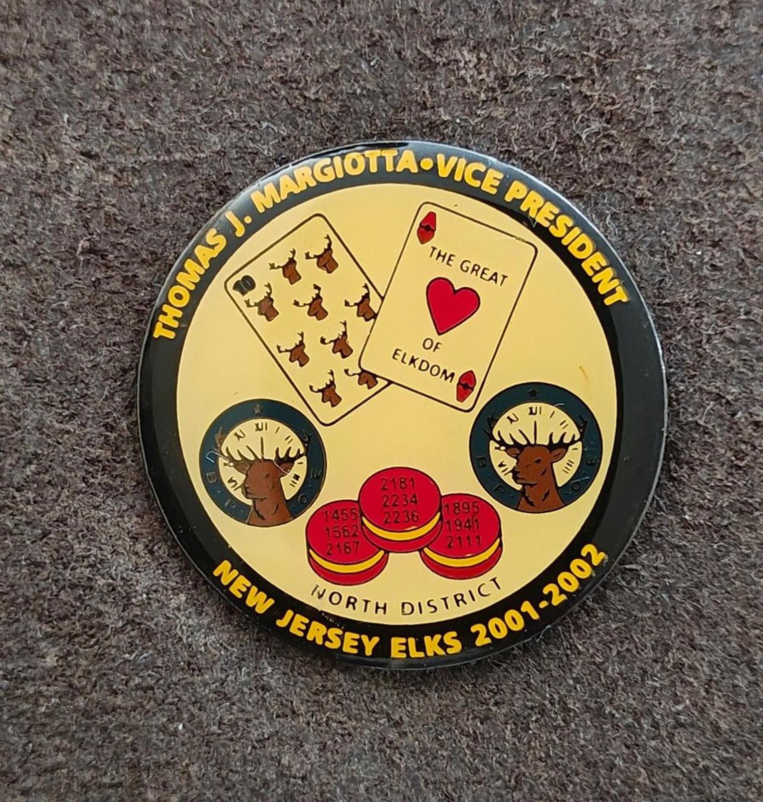Round gold tone lapel pin featuring a yellow emblem with black border and text.