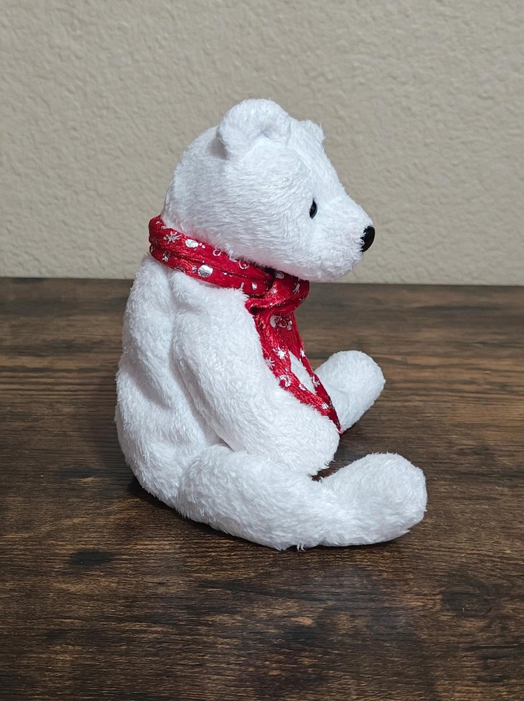 White bear plush sitting and facing right, wearing red patterned scarf