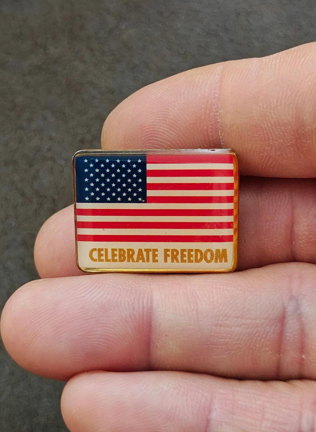 Patriotic flag enamel pin with “CELEBRATE FREEDOM” on gold-tone border