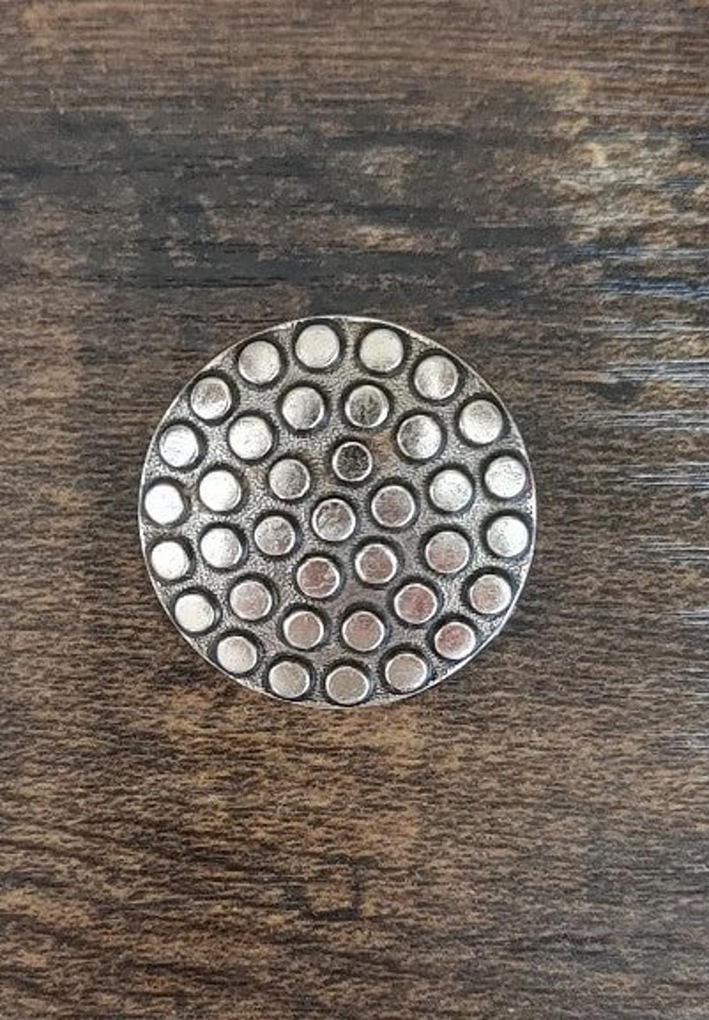 Round scarf clip with tightly packed circular dots and silvery metal finish