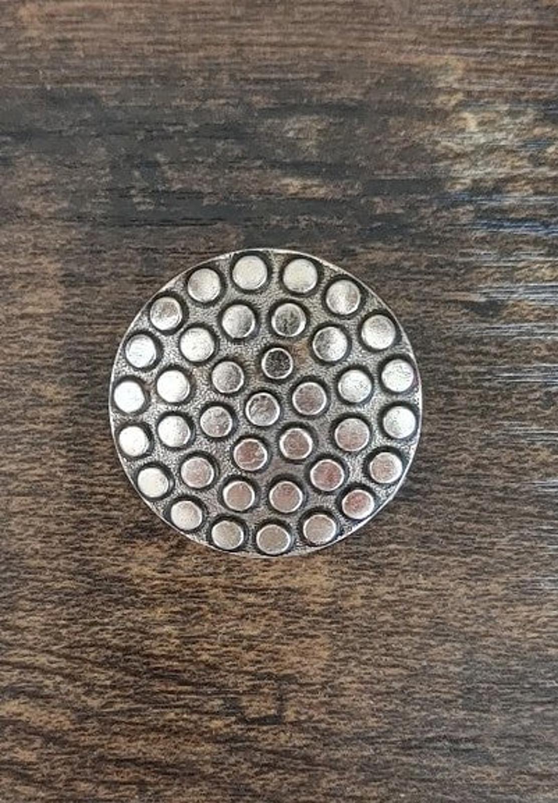 Round scarf clip with tightly packed circular dots and silvery metal finish