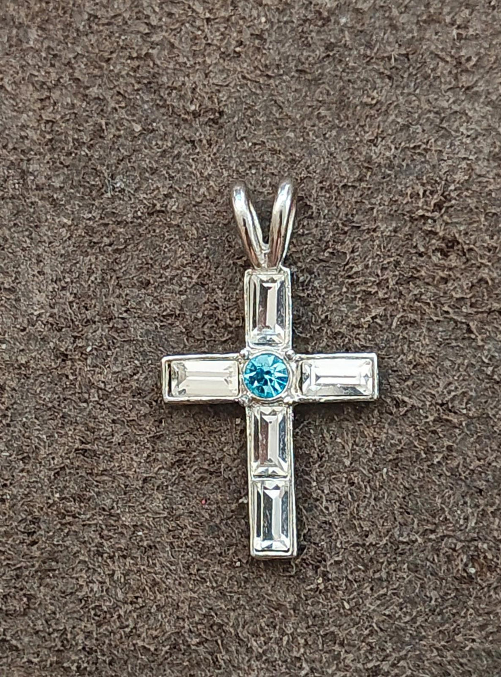 Silver tone rhinestone cross pendant with blue round center and clear rectangular stones.