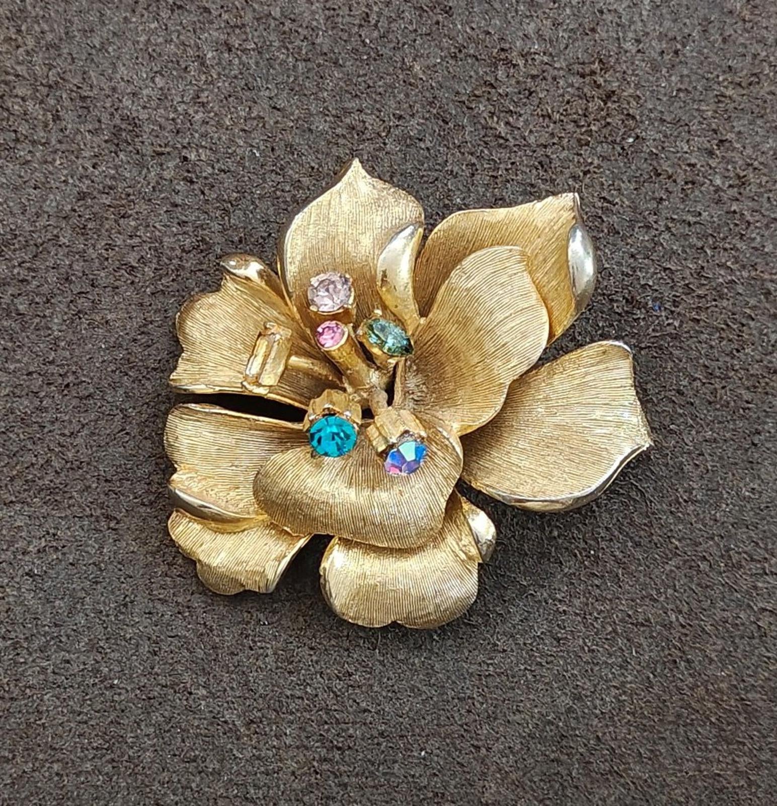 Gold-tone flower brooch with textured petals and blue, pink, and clear stones