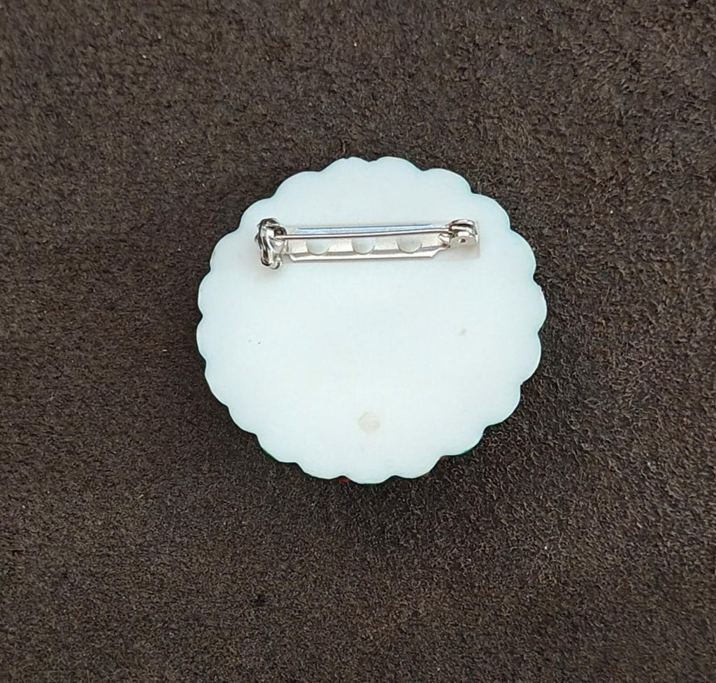 Back of a white plastic bear wreath pin with metal safety clasp