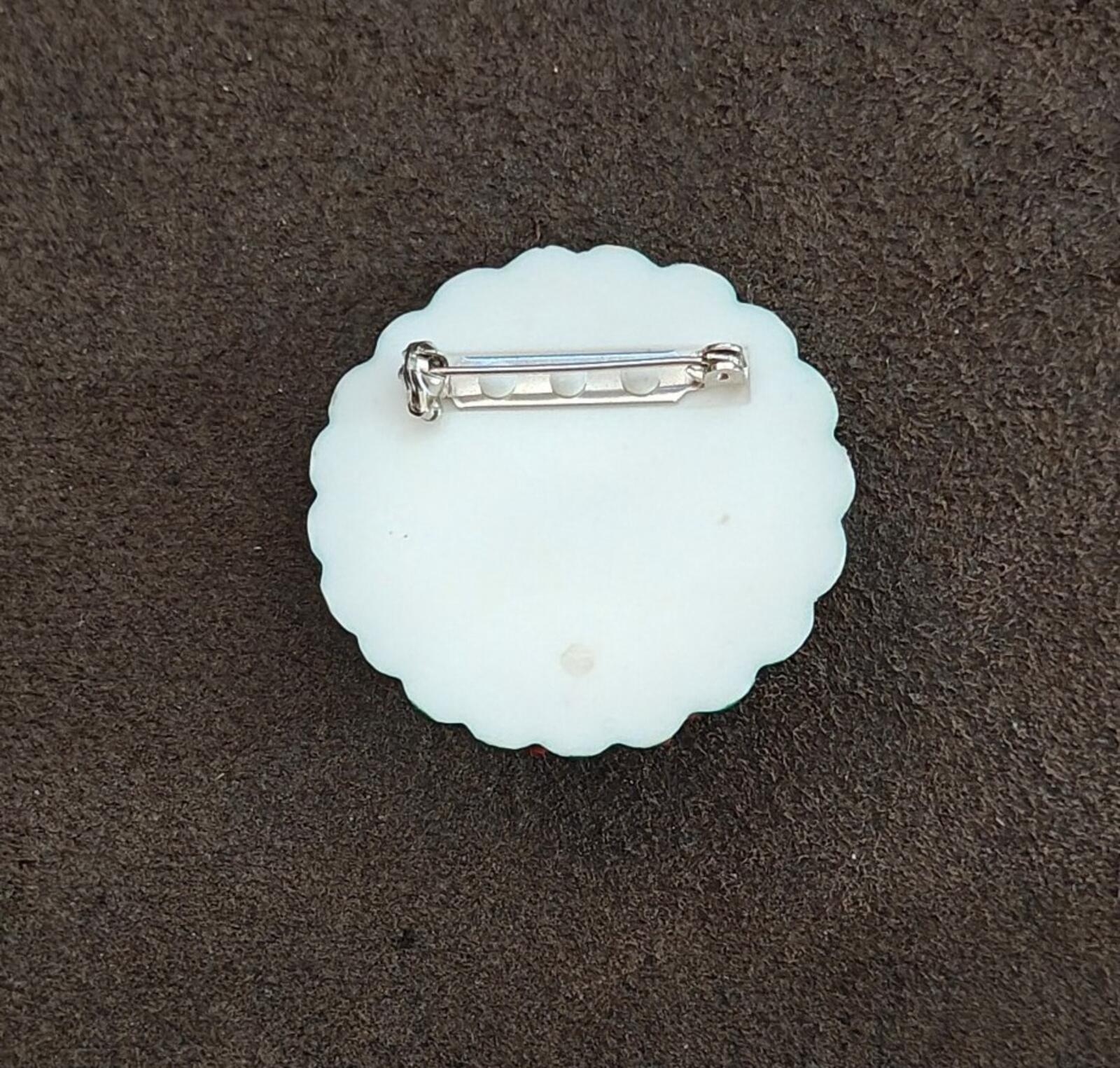 Back of a white plastic bear wreath pin with metal safety clasp