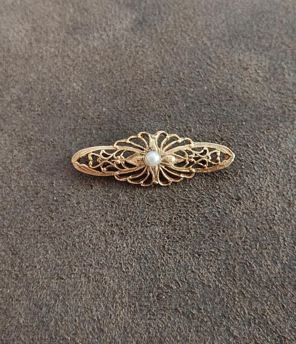 Gold-tone filigree bar brooch with small central faux pearl